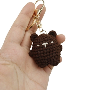 Handmade brown crochet bear keychain with golden metal ring on white background