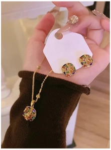 Detailed macro view of gold-plated necklace and square zircon stud earrings set
