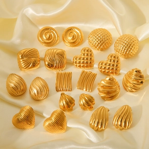 Set of ten geometric 18K gold plated stainless steel stud earrings on cream silk fabric
