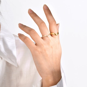 Detailed view of stacked gold chevron rings with zircon accents on a model's hand
