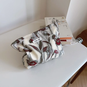 Close-up of elegant floral embroidery on a minimalist beige fabric cosmetic bag pouch