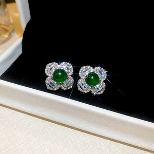 Macro shot of emerald flower stud earrings with marquise zircons in a black gift box