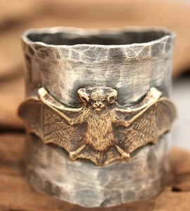 Macro shot of a vintage silver hammered ring band featuring a detailed bronze bat