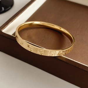 Macro view of gold mahjong tile patterns and Chinese characters engraved on the metal bangle