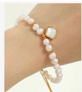Detail of freshwater pearl bracelet with gold shell charm on a woman's wrist
