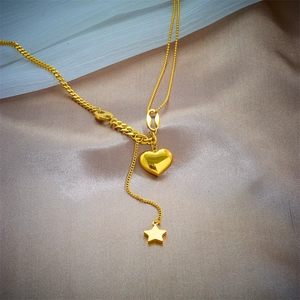 Minimalist gold heart and star tassel necklace displayed on premium champagne silk fabric