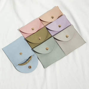 Macro view of multi-color microfiber jewelry pouches with snap buttons and gold bracelet