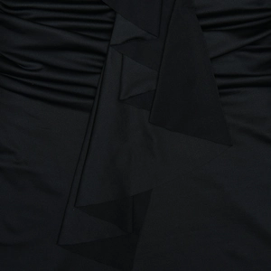 Gros plan du tissu plissé noir montrant la texture et le drapé de la robe ajustée