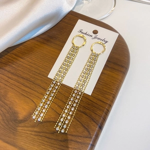 Detail of long gold tassel earrings with micro-set zircons on a white jewelry card