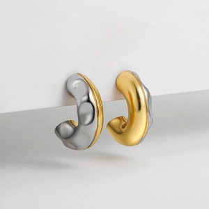 Detailed macro view of two-tone gold and silver C-shaped earrings with hammered texture