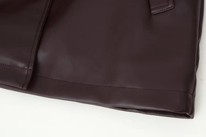 Detail of the reinforced stitching and lychee grain texture on a dark PU leather jacket hem