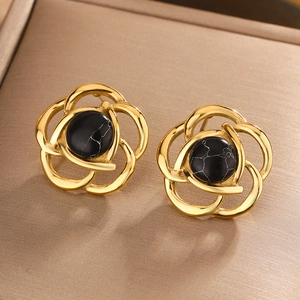Macro shot of camellia stud earrings with black turquoise stones in gold frames