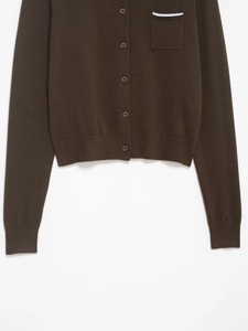 Detail of brown knit cardigan featuring button closure and contrast white trim on pocket