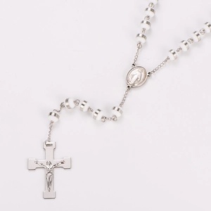 Detail of silver rosary necklace with Miraculous Medal and crucifix on white background