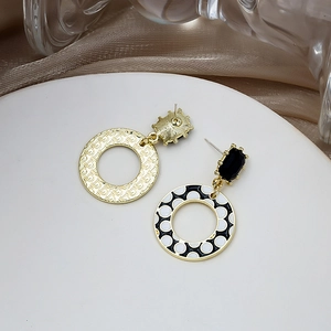 Golden geometric earrings featuring black rectangular drops and polka dot enamel rings