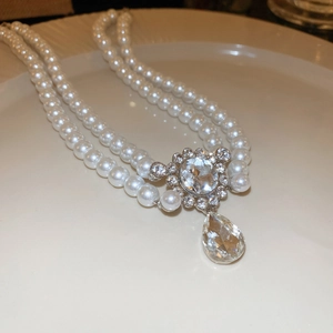 Close-up of double-layer pearl necklace featuring a sparkling teardrop crystal pendant