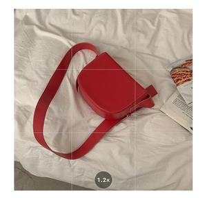 Detail of red PU leather saddle bag featuring a wide strap and minimalist flip cover