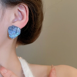 Close-up of blue irregular resin stud earrings with natural stone texture on model