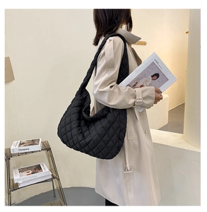 Quilted oversized shoulder bag shown on model in stylish beige coat and casual setting