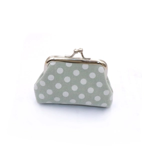 Detailed view of green canvas kiss-lock coin purse with white polka dots and metal clasp