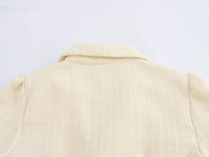 Dettaglio della trama in tweed e dello scollo su un abito blazer color crema
