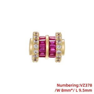 Detailed macro view of gold-plated charm bead with clear zircons and red emerald-cut stones