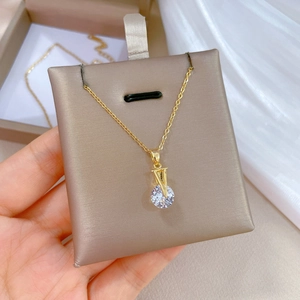 Macro shot of gold V-shaped pendant with round zircon on a grey display card