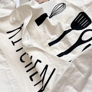Detailed view of the linen apron fabric with kitchen utensil prints and lettering