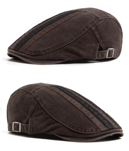 Detail view of brown flat cap with black stripes and silver metal adjustment buckle