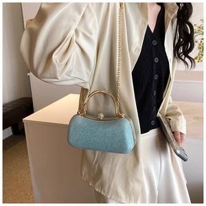 Close-up of light blue glitter evening bag with gold metal handle and rhinestone clasp