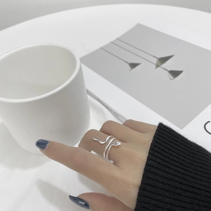 Close-up of a silver vintage snake wrap ring on a finger with minimalist background