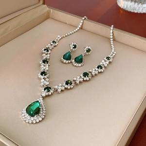 Macro shot of silver jewelry set with green teardrop gems and crystals in a box