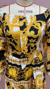 Detailed view of Baroque print dress with V-neck tie and gold patterns on mannequin