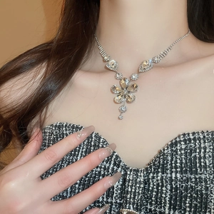 Close-up of sparkling crystal flower pendant necklace on model's neck for elegant styling