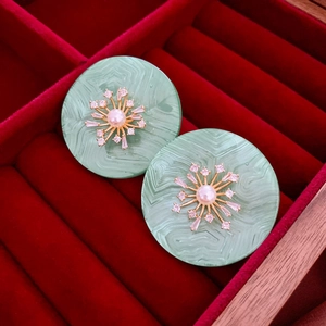 Détail de boucles d'oreilles vintage vert menthe avec zircon étoilé et perle centrale