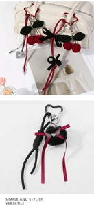 Macro detail of hand-woven cherry and plush heart pendants on a stylish handbag