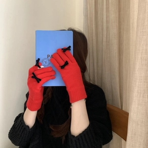 Detail of red knitted gloves featuring elegant black velvet bow and warm tactile texture