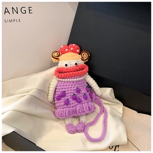 Detailed view of a handmade purple crochet doll bag with pearl necklace and berry accents