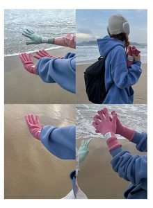 Detail view of mint green and pink wool knit gloves with handmade labels on the beach