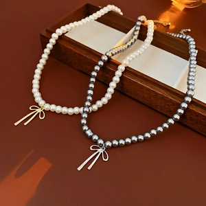 Détail de colliers de perles vintage avec nœuds en métal en crème et gris perle