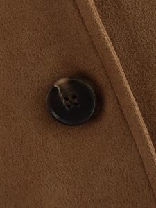 Gros plan sur la texture du blazer en daim marron et le bouton en résine ambrée foncée