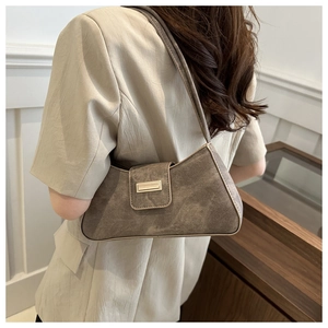 Detailed view of grey faux suede baguette bag with metal buckle on woman shoulder