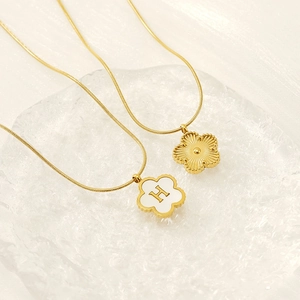 Macro view of 18K gold plated clover pendants with shell letter H on a snake chain