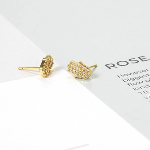 Detailed close-up of golden Hamsa hand earrings with pavé white zircon stones