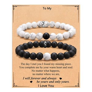 Matching couple bracelets with heart magnets and white stone beads on a gift card