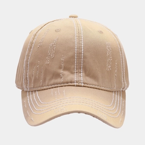 Detail of khaki washed canvas baseball hat with white contrast stitching and distressed holes
