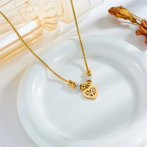 Gold tree of life heart pendant necklace with zircon accents on a white ceramic plate