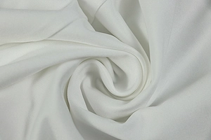 Close-up of white knit fabric with soft texture and spiral drape detailing for dresses