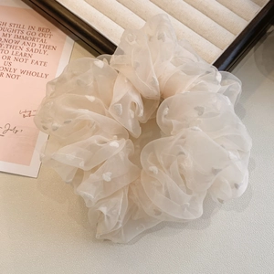 Gros plan d'un chouchou en tulle avec broderie coeur ivoire et tissu en organza