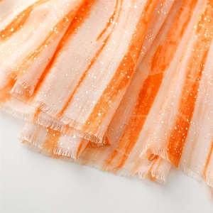 Detail of orange and white gradient scarf with gold foil accents and raw frayed edges